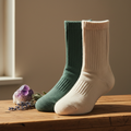 Premium organic cotton crew socks in forest green on a natural wood surface with crystals and dried herbs